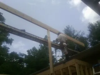 Carpenter setting a ridge beam over a new addition frame — Ice Dam Removal by Roofing Brothers in Maybell