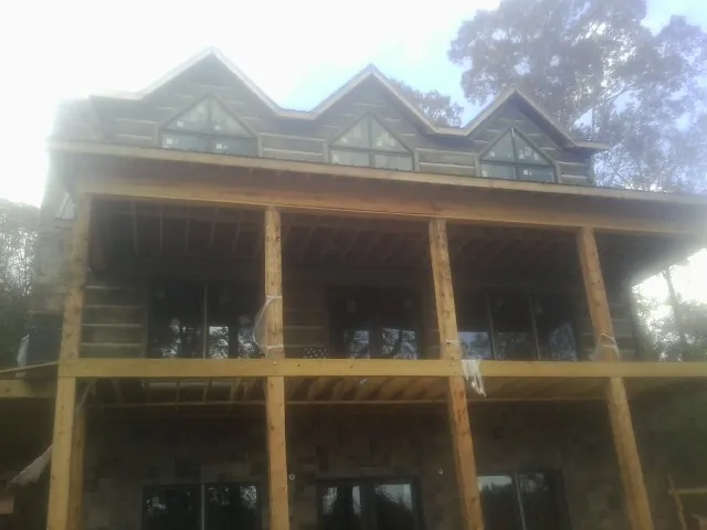 Dormers and porch framing on a large log home under construction — Roof Coating work by our crew in Maybell