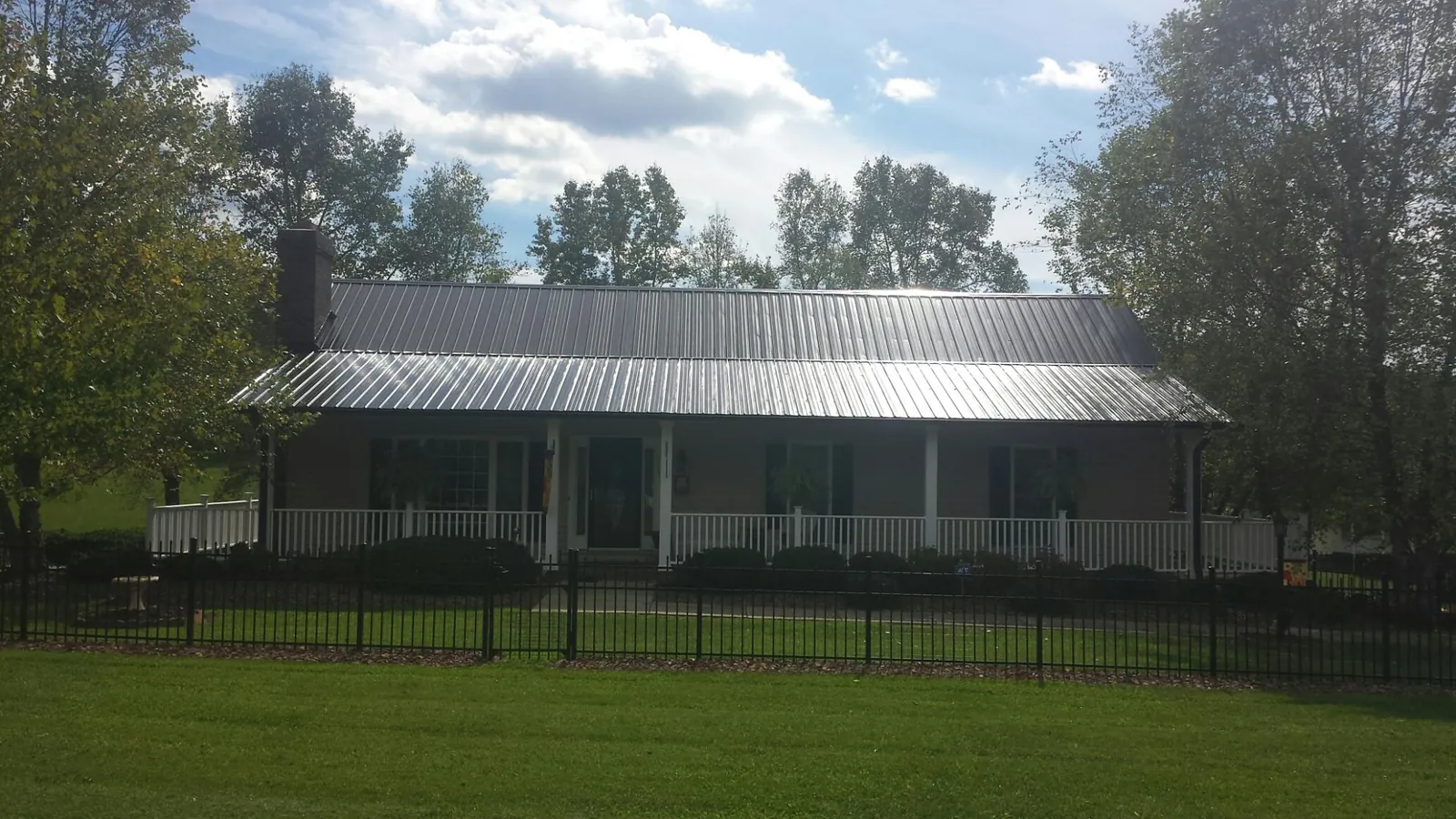 Gray metal roof on a brick ranch with a full width front porch — Gutter Guard Installation work by our crew in Maybell