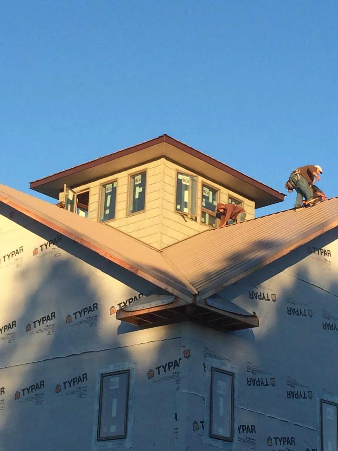 Roofers working around a rooftop cupola on a new metal roof at sunset — Roof Waterproofing in Maybell by Roofing Brothers